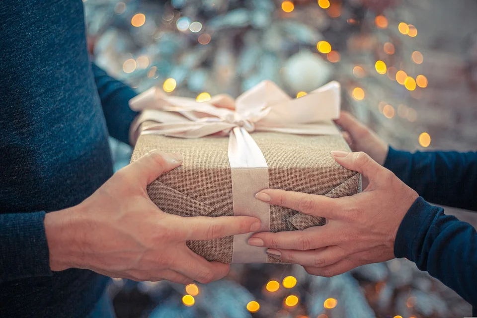 a girl is holding a gift for man hand in hand